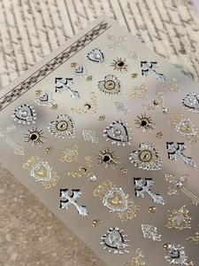 Macro shot of 3D baroque nail art stickers with metallic gold and silver crosses and hearts