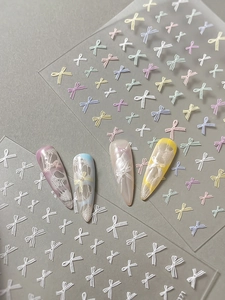 Detail showing colorful 3D bow nail stickers with lace patterns on nail tips