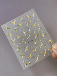 Macro shot of gold metallic star nail art stickers with faceted rhinestones on clear backing