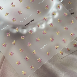 Pink and purple floral nail stickers with gold glitter accents on pink plush background