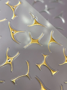 Macro detail of gold metallic four-pointed star nail stickers with inlaid crystal rhinestones