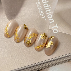 Exquisite 3D gold flower nail charms on pearlescent apricot press-on nails
