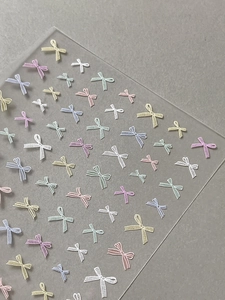 Close-up of 3D bow nail stickers with colorful macaron knit texture and relief detail