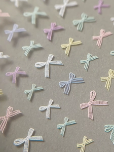 Close-up of 3D bow nail art stickers with fine mesh texture in pastel macaron colors