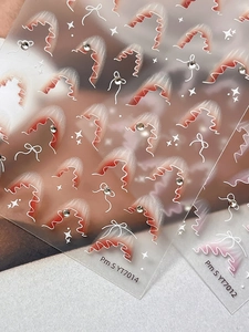 Primo piano di adesivi per unghie con pizzo rosa e fiocchi bianchi con strass fini