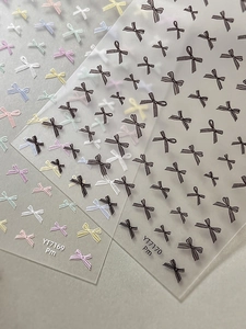 Detail view of 3D embossed bow tie nail stickers in pastel macaron and black colors