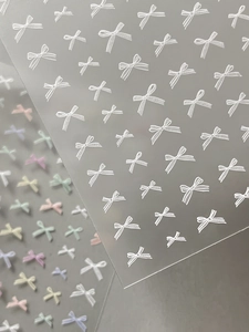 Detailed view of 3D bow nail stickers with embossed textures and pastel macaron colors