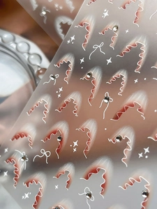 Vista macro di adesivi per unghie in stile francese con linee rosse, fiocchi e strass