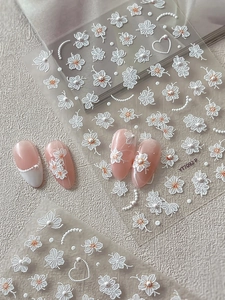 Detail von 3D geprägten weißen Blumen-Nagelstickern mit Perlenkette und Herzmotiven