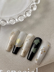 Detail of long coffin nails with maple leaf art, gold foil, and crystal rhinestones