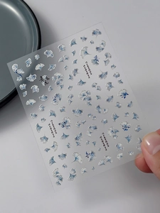 Close-up of blue ginkgo leaf nail art stickers with silver foil and Chinese calligraphy
