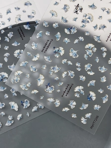 Detail showing blue and white ginkgo leaf nail art stickers with gold foil outlines