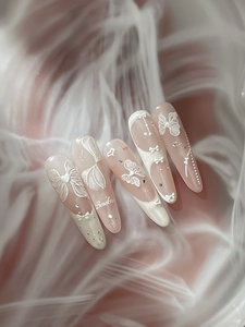 Détail de nœuds 3D et perles sur faux ongles rose amande avec décoration en dentelle