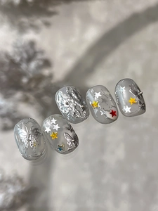 Macro detail of translucent gray-white nails with 3D silver butterflies and star sequins