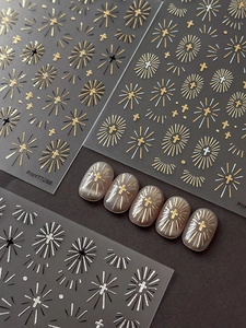 Detailed view of silver and gold cross radiating sunburst nail art stickers on black base