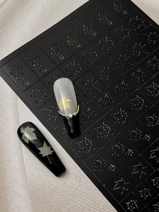Detailed view of autumn maple leaf nail art decals on long trapezoid false nails