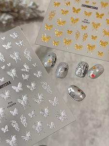 Detail of 3D gold and silver butterfly nail art stickers with metallic relief textures
