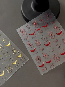Detail of silver and red cross nail stickers with moon and starburst patterns