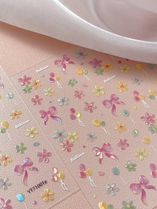 Vista macro di adesivi 3D per unghie con fiocchi rosa, fiori e palloncini colorati