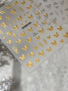 Macro shot of 3D embossed gold and silver butterfly nail stickers with flame patterns