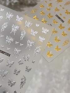Macro view of 3D metallic butterfly nail stickers in gold and silver with embossed textures
