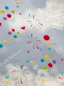 Macro detail of 3D embossed colorful balloon and red heart motifs on nail art stickers