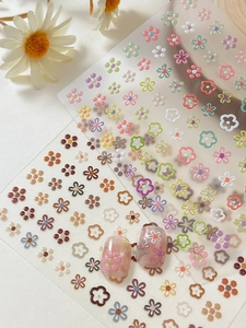 Macro detail of 3D floral nail stickers featuring solid and hollow five-petal flower designs