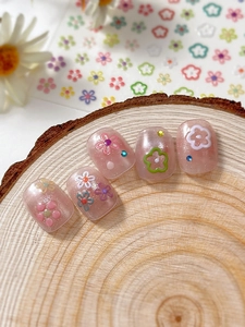 Detailed view of pink shimmer press-on nails with 3D floral and rhinestone accents