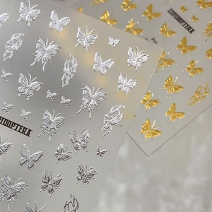 Golden and silver 3D butterfly nail art decals with embossed metallic texture and patterns