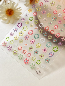 3D macro detail of colorful embossed floral nail stickers with gold accents and macaron tones