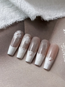 Macro view of long trapezoid nails with white lace patterns and pearl accents