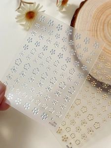 Macro detail of gold and silver floral nail art stickers with delicate petal and dot patterns