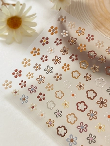 Close-up of golden embossed flower nail art stickers with textured 3D floral patterns