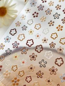 Macro view of gold foil floral nail art stickers with minimalist flower patterns