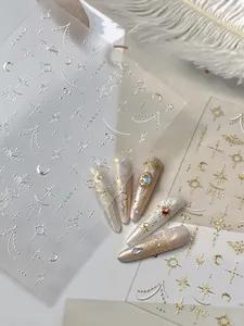 Dettaglio macro di adesivi per unghie in oro e argento con motivi celesti di luna e sole