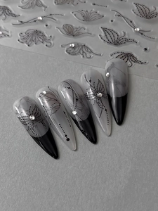 Detail of long pointed black and white gradient fake nails with rhinestones and art