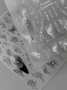 Macro shot of 3D embossed butterfly nail art stickers with black and white floral patterns