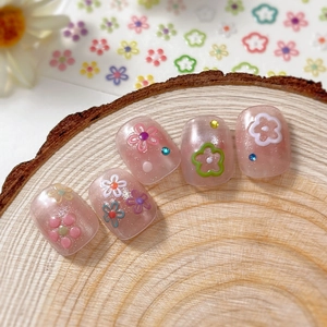 Short round translucent pink press-on nails with glitter, flower patterns and rhinestones