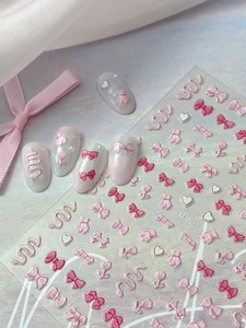 Macro detail of 3D embossed nail stickers featuring pink bows and sweet heart patterns