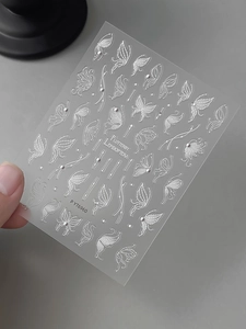 Macro view of white embossed butterfly nail stickers with delicate glitter patterns