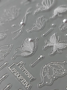 Detailed macro view of 3D embossed butterfly nail stickers with pearly relief texture