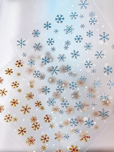 Macro detail of bronzing snowflake nail decals in gold and laser silver for winter nail art