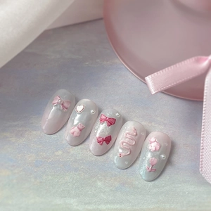 Pink bow embossed press-on nails with 3D pearls and cute bear designs on purple background