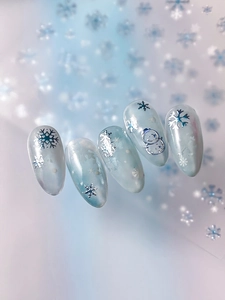 Macro view of blue gradient nail stickers with silver snowflakes and snowman designs