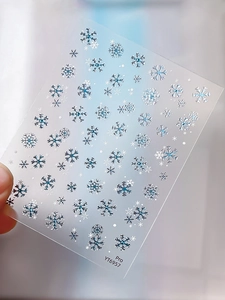 Detail of winter blue and silver snowflake nail art stickers on a translucent sheet