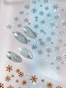 Detailed macro view of bronzing snowflake and snowman nail stickers with metallic foil effect