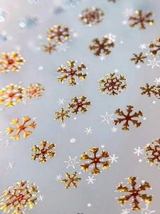 Macro shot of gold bronzing snowflake nail stickers with shimmering metallic texture