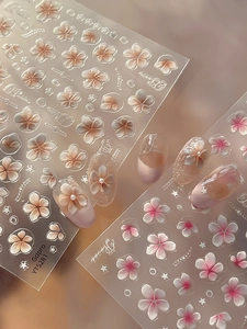 Macro shot of 5D embossed nail stickers featuring pink floral patterns and pearl details