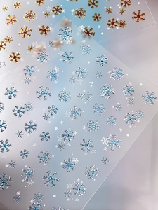 Macro shot of gold and silver laser snowflake nail stickers with festive winter patterns