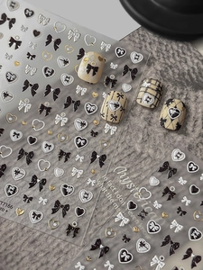 Detail of 3D embossed nail stickers featuring gold bows and heart motifs on a dark background